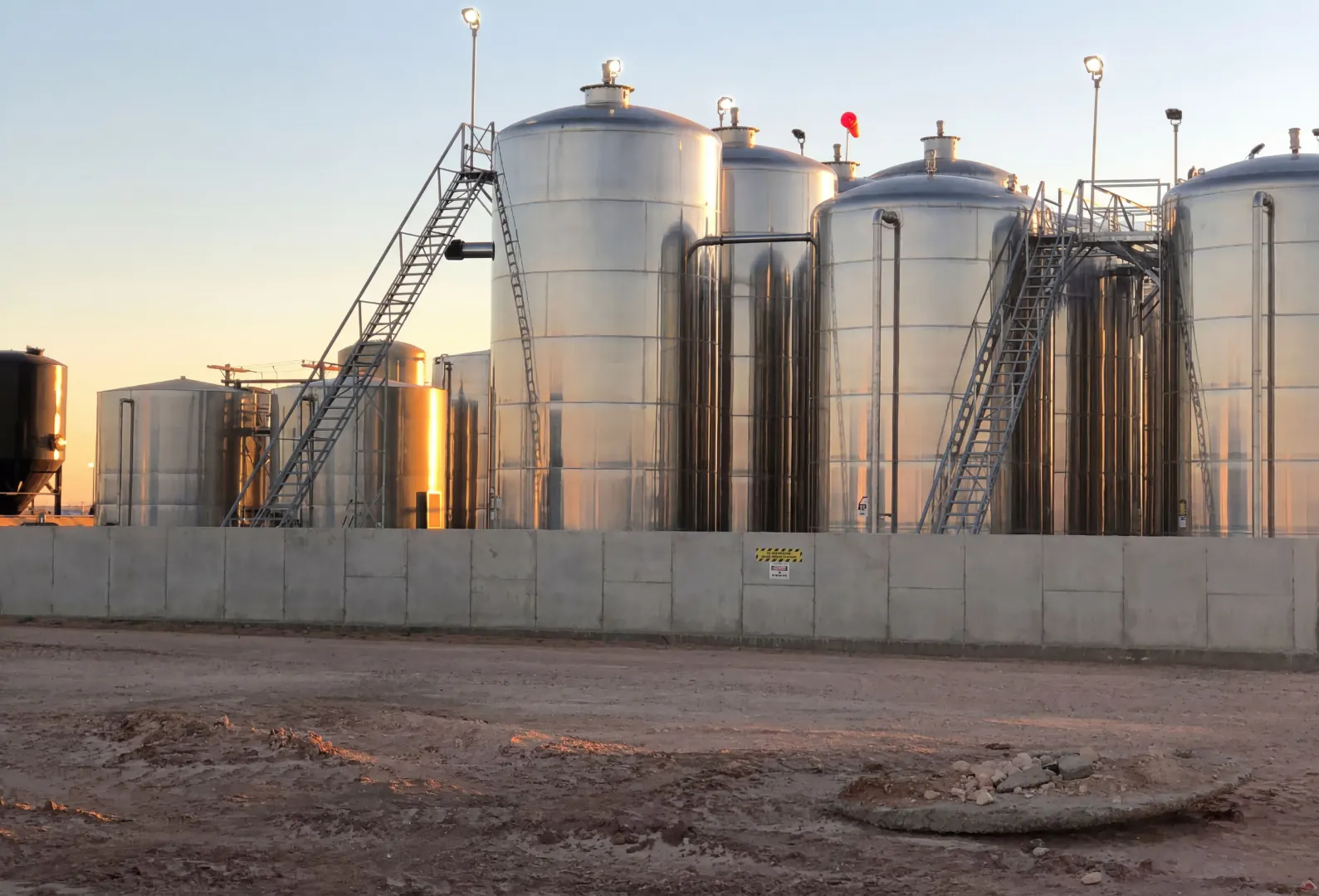 Stainless storage and process tanks at sunset